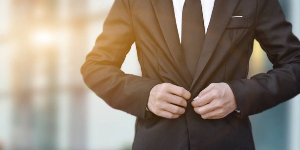 Close-up van zakenman in zwart pak strikken van de stropdas. - Foto, afbeelding