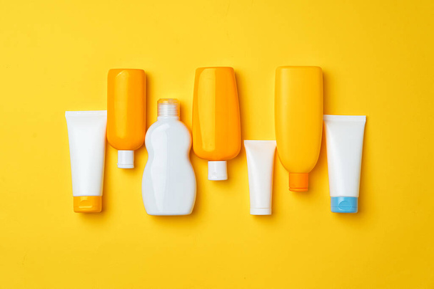 Collection of sunscreen cream bottles on yellow background - Valokuva, kuva