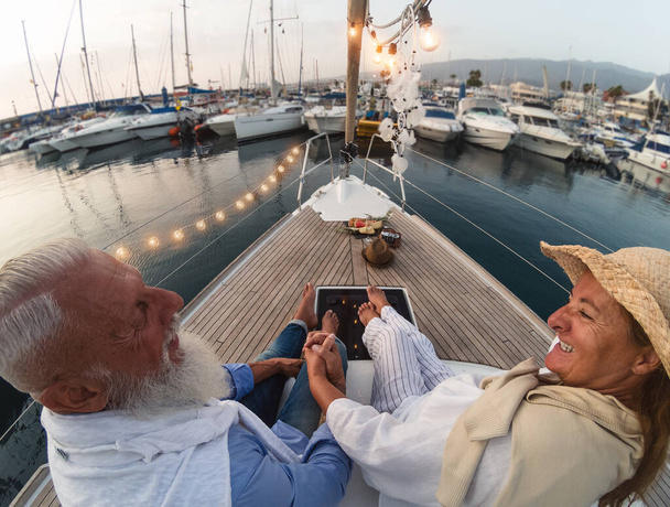 Starsza para na wakacjach na żaglówce - Szczęśliwi starsi ludzie dobrze się bawią świętując rocznicę ślubu na wycieczce łodzią - Koncepcja relacji miłosnych i stylu życia podróży - Zdjęcie, obraz