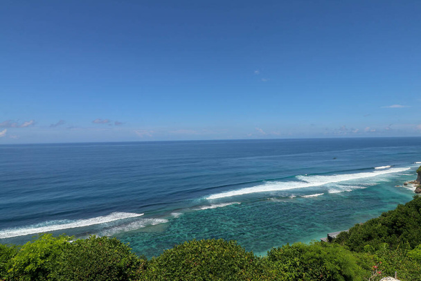 Голубой закат на океане с большими волнами, скалами и утесами. Остров Бали с его уникальной и экзотической природой. Восход солнца над морем и океаном. Призрачная синева на закате
. - Фото, изображение