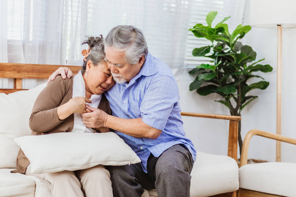 Retired Asian senior elderly wife pain from heart attack disease or illness with serious or worried husband take care at home. Medical emrgency treatment and health care insurance protection concept - Foto, Imagen