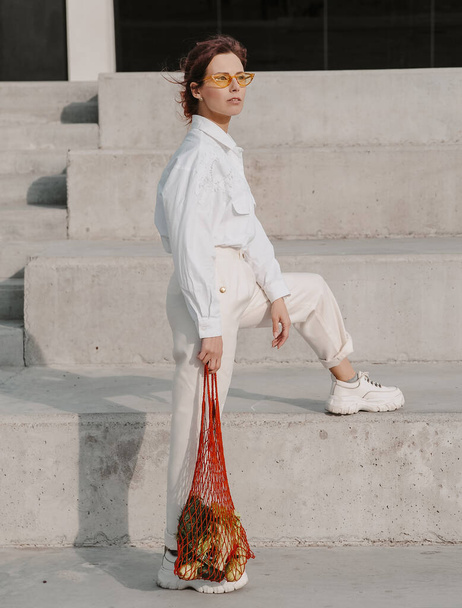 Mujer de moda sostiene bolsa de artesanía ecológica con verduras
. - Foto, imagen