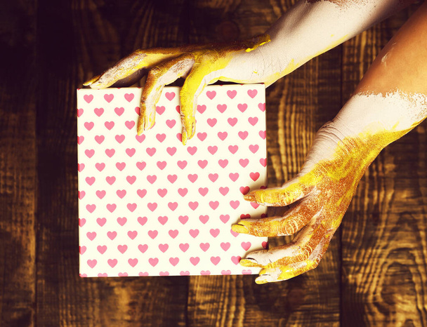 female hands holding valentine present on brown vintage studio background - Foto, immagini