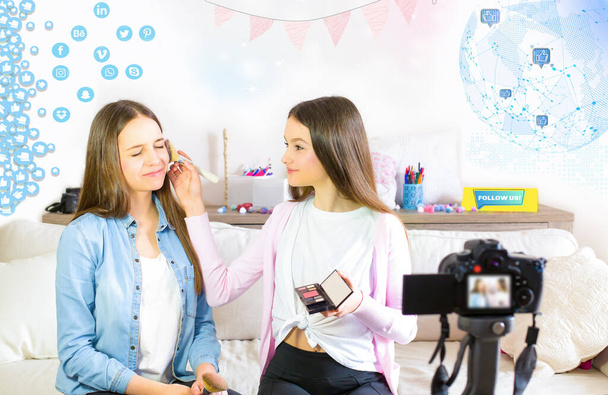 Δύο όμορφα blogger χαριτωμένα κορίτσια παρουσιάζουν καλλυντικά προϊόντα ομορφιάς και μεταδίδουν ζωντανά βίντεο στο κοινωνικό δίκτυο. Επικεντρώσου στην επιρροή των έφηβων μπλόγκερ. Beauty blogger και vlog concept για έφηβους οπαδούς. - Φωτογραφία, εικόνα