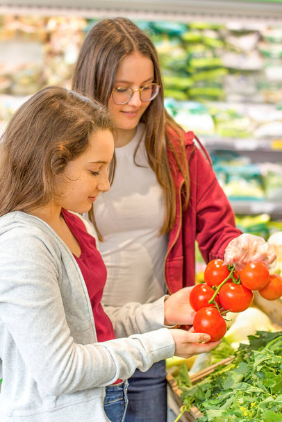 Tini lányok vásárolnak a szupermarketben. A fiatalok tudatos, organikus és egészséges döntést hoznak. - Fotó, kép