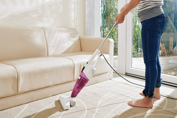 Woman vacuum cleaning living room twice a day when staying at home during quarantine - Photo, Image