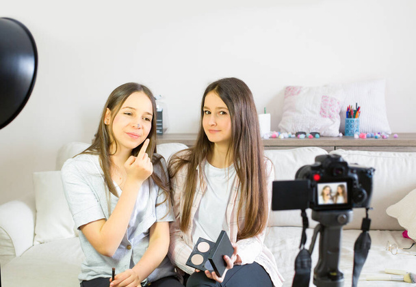 Two teen bloggers presenting beauty products and broadcasting live videos on social networks. Focus on teen girls influencer bloggers. Beauty bloggers and vlog concept. - Фото, зображення