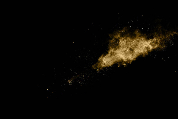 Golden powder explosion on black background. Colored cloud. Colorful dust explode. Paint Holi. - Photo, Image