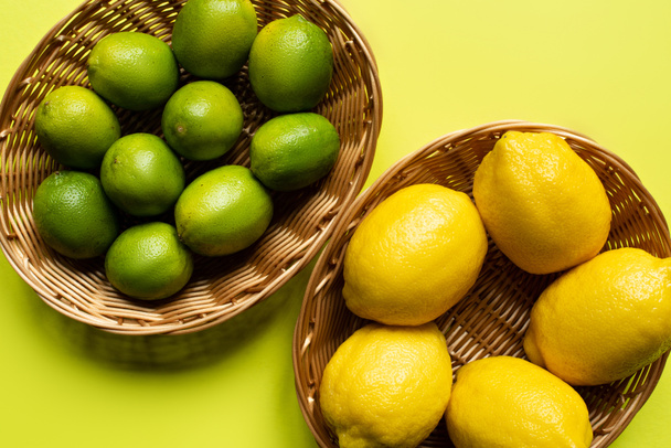 Draufsicht auf reife Limetten und Zitronen in Weidenkörben auf buntem Hintergrund - Foto, Bild
