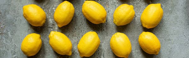 pose plate avec des citrons jaunes mûrs sur surface texturée en béton, culture panoramique - Photo, image