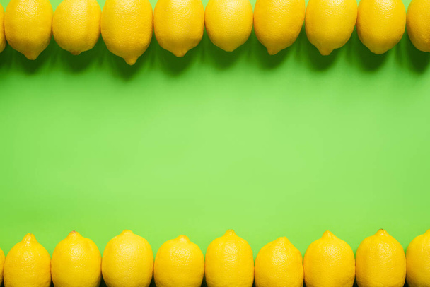Draufsicht auf reife gelbe Zitronen auf grünem Hintergrund mit Kopierraum - Foto, Bild