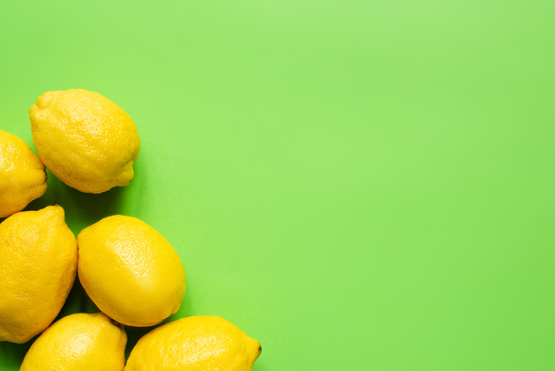 top view of ripe yellow lemons on green background with copy space - Foto, Bild