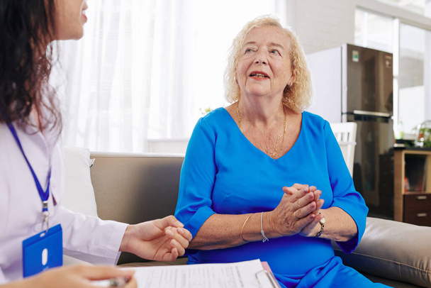 Donna anziana che parla con il medico che la visita a casa e scrivere prescrizione medica - Foto, immagini