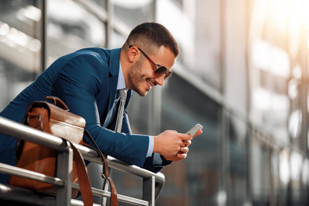 Attraktive junge Geschäftsmann mit einem Smart Phone.Portrait von schönen Geschäftsmann im Freien in der Stadt. - Foto, Bild