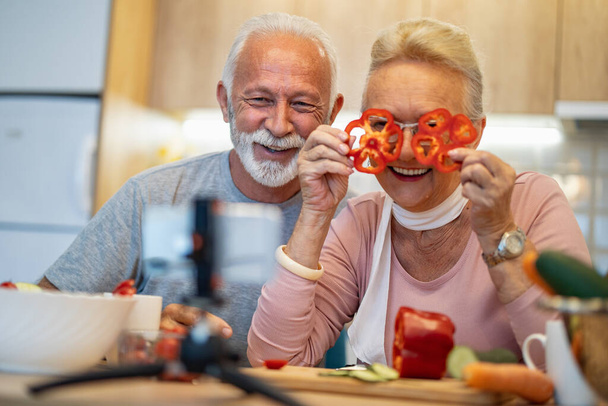 Seniorenpaar dreht Video über vegetarisches Essen in der Küche. Blogging-Konzept. Menschen, Essen und Trinken, Technologie und Lebensstilkonzept. - Foto, Bild