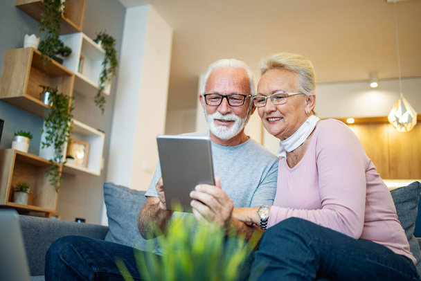 Seniorenpaar sitzt zu Hause und nutzt Tablet.Online-Shopping.Menschen und Technologie-Konzept. - Foto, Bild