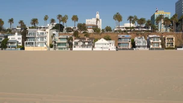 Kaliforniya yazları plaj estetiği, güneşli mavi gökyüzü, kum ve deniz kenarındaki birçok farklı hafta sonu evi. Deniz kenarındaki binalar, Santa Monica Pasifik Okyanusu kıyısındaki emlak merkezi, Los Angeles CA USA - Video, Çekim