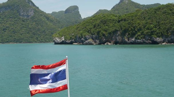 Group of Islands in ocean at Ang Thong National Marine Park. Archipelago in the Gulf of Thailand. Idyllic turquoise sea natural background with copy space. Waving flag as national symbol on the boat - Photo, Image