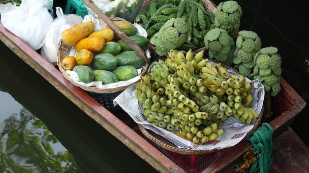 Εικονική ασιατική Lat Mayom πλωτή αγορά. Khlong κανάλι του ποταμού, μακριά ουρά βάρκα με τροπικά εξωτικά πολύχρωμα φρούτα, βιολογικά τοπικά καλλιεργούμενα λαχανικά. Κάτοψη της συγκομιδής και των τροφίμων του δρόμου σε ξύλινο κανό. - Φωτογραφία, εικόνα