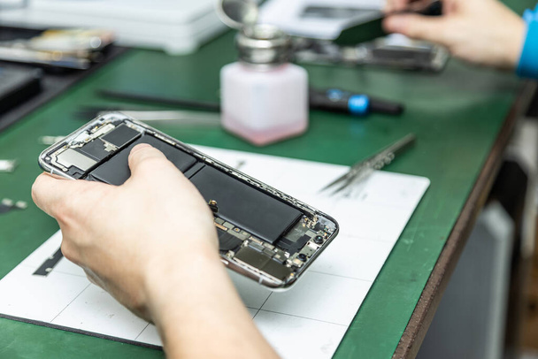 técnico irreconhecível reparar telefone inteligente em sua oficina de reparação
 - Foto, Imagem