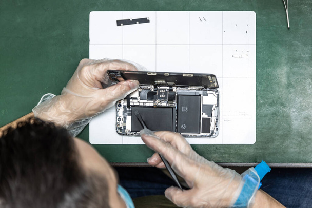Unbekannter repariert Smartphone in seiner Werkstatt - Foto, Bild