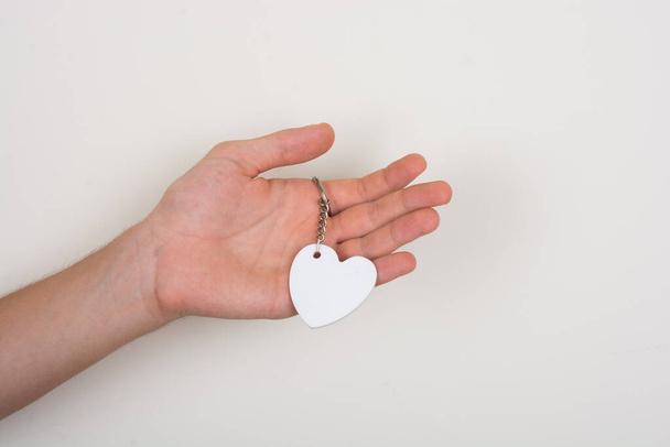 Oggetto bianco a forma di cuore in mano su sfondo bianco - Foto, immagini