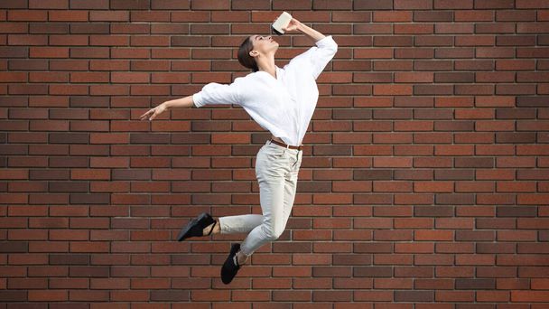 Jumping young woman in front of buildings, on the run in jump high - 写真・画像