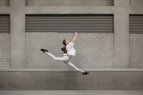 Jumping young woman in front of buildings, on the run in jump high - Foto, Imagem