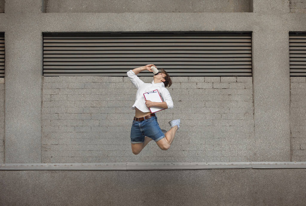 Jumping young man in front of buildings, on the run in jump high - Foto, Imagen