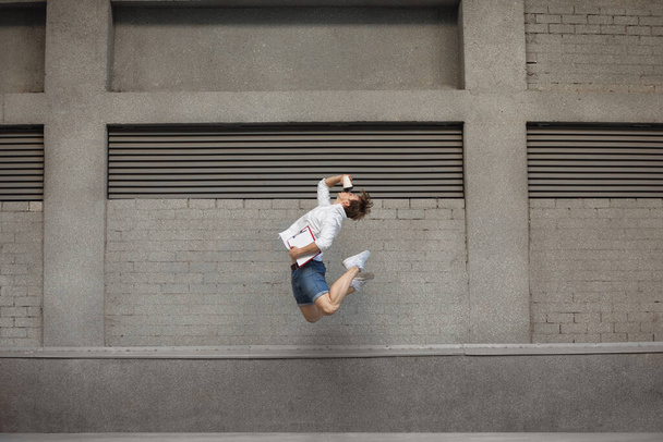 Jumping young man in front of buildings, on the run in jump high - Fotografie, Obrázek