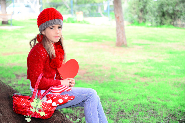 Belle fille avec chapeau au crochet rouge tenant grand coeur de feutre Valentine
 - Photo, image