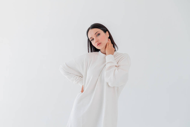 Beautiful adult girl model in white sweater hoody isolated over gray white background. Copy space - Valokuva, kuva