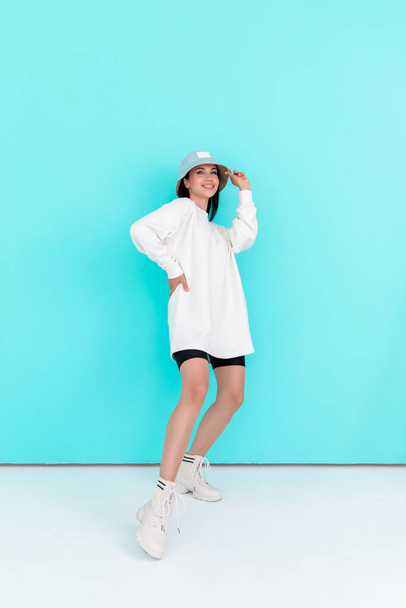 Fashion girl in blank sweatshirt jacket in summer hats on a blue background. Copy space - Photo, Image