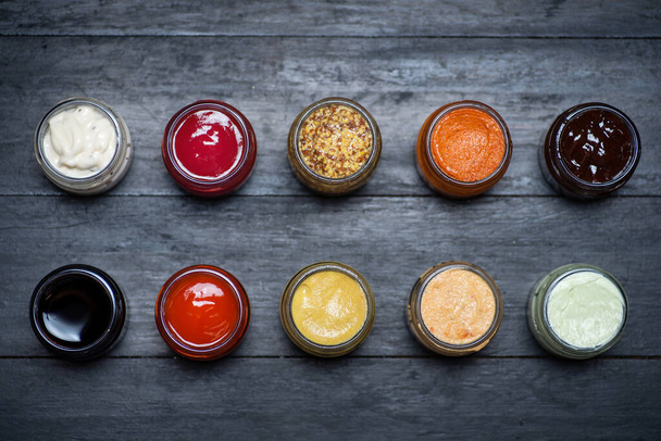 Large collection of sauces and spiced spreads in small jars as mayo ketchup mustard soy sauce and many more - Photo, Image
