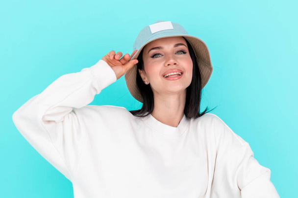 Beautiful girl model in white hoody in hat on a blue background - Foto, afbeelding