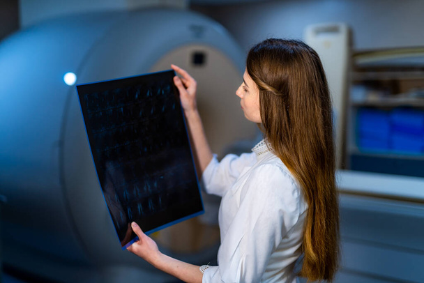 Competent doctor reading x-ray near the magnetic resonance imaging machine. - Valokuva, kuva