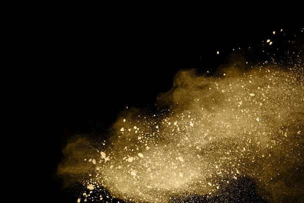 Golden powder explosion on black background. Colored cloud. Colorful dust explode. Paint Holi. - 写真・画像
