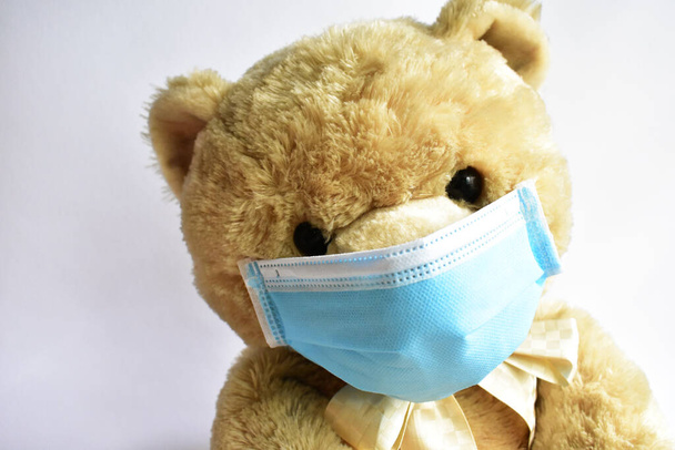 Carino orso bruno con maschera medica blu su sfondo bianco. Medico orso indossare maschera protettiva per la diffusione del virus della malattia CoV-2 Corona virus Malattia di quarantena, stare al sicuro, bambini - Foto, immagini