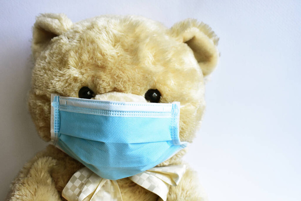 Cute brown bear with blue medical mask in white background. Doctor bear wearing face mask protective for spreading of disease virus CoV-2 Corona virus Disease quarantine, stay safe, children - Photo, Image