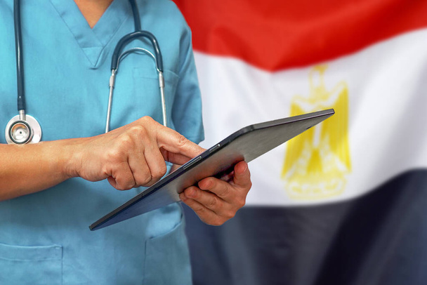 Хирург или врач с помощью цифровой таблетки на фоне египетского флага. Медицинское оборудование или медицинская сеть, технологии и диагностика в Египте
. - Фото, изображение