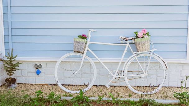 Ρετρό ποδήλατο με δύο καλάθια με λουλούδια στο φόντο ενός μπλε σπιτιού. Διακόσμηση κήπου σε στυλ Προβηγκία - Φωτογραφία, εικόνα