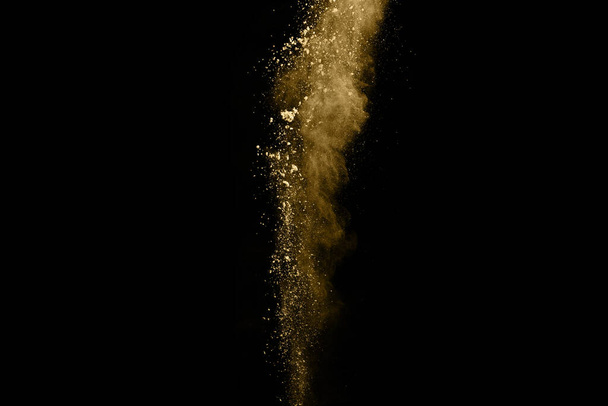 Golden powder explosion on black background. Colored cloud. Colorful dust explode. Paint Holi. - Foto, afbeelding