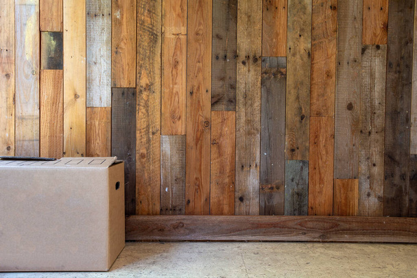 cardboard moving boxes in empty room with wooden wall background and copy space, moving in new flat or house concept, retro design - Foto, imagen