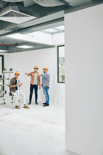 Вертикальный длинный снимок, изображающий типичный рабочий день современных профессиональных инженеров-строителей, копировальное пространство - Фото, изображение