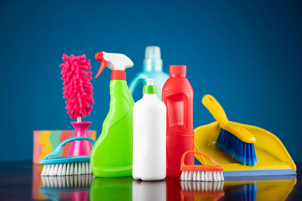 Tema de limpieza de casa y oficina. Kit de limpieza colorido sobre mesa marrón shing y fondo azul. - Foto, imagen