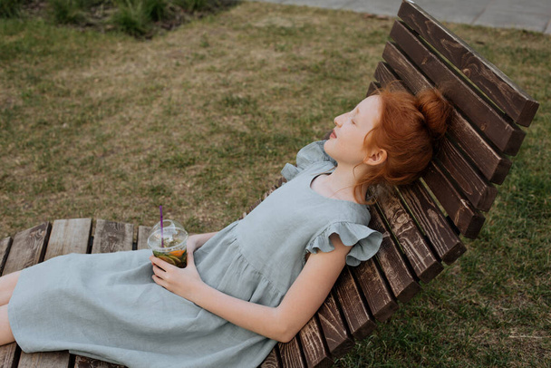 Punapää tyttö makaa puinen riippumatto nauttia hyvästä säästä. - Valokuva, kuva