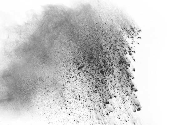 partículas de carbón vegetal sobre fondo blanco, polvo abstracto salpicado sobre fondo blanco, congelar el movimiento del polvo negro explotando o lanzando polvo negro. - Foto, Imagen