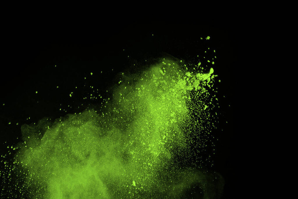 The movement of abstract dust explosion frozen green on black background. Stop the movement of powdered green on black background. Explosive powder green on black background. - Фото, изображение