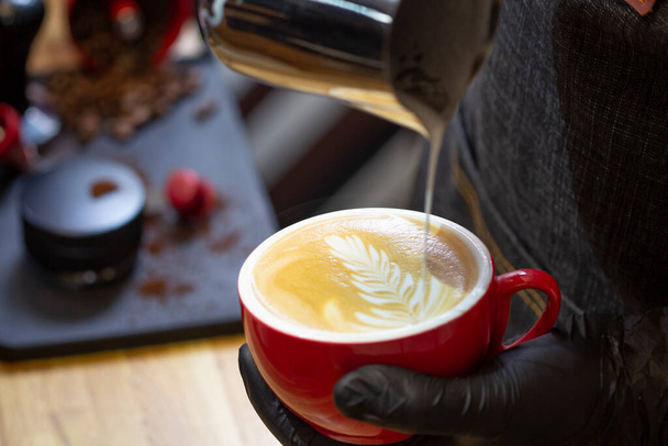Barista makes latte art drawing on cappuccino coffee. - Fotó, kép