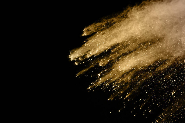 Golden powder explosion on black background. Colored cloud. Colorful dust explode. Paint Holi. - Фото, изображение